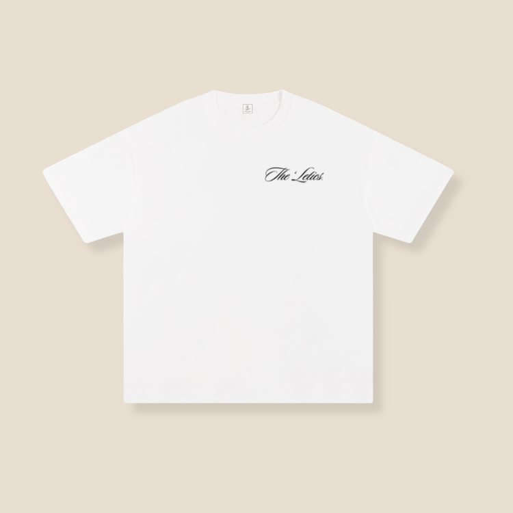 White t-shirt with 'The Leleis' logo on a beige background