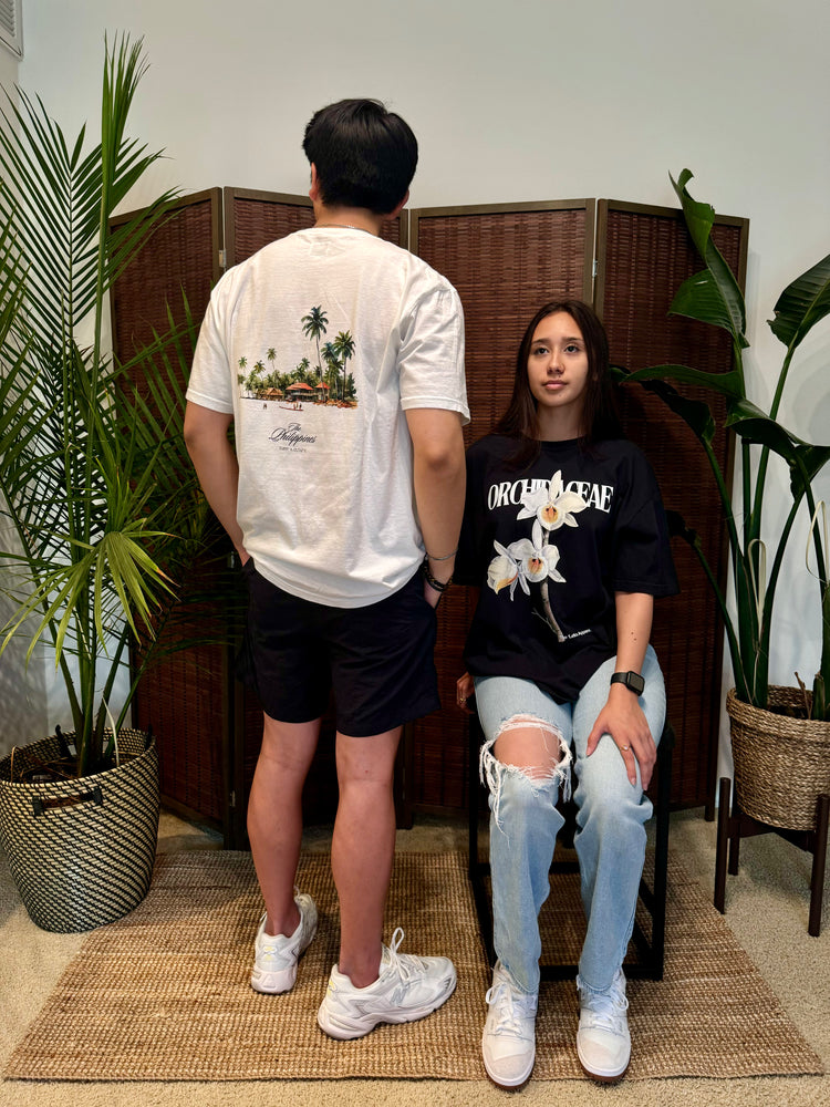 Models standing on a set wearing graphic tees of homeland tee facing the wall.