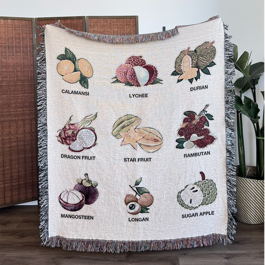 Blanket with illustrations of various fruits and their names on a wooden floor. Calamansi, Lychee, Durian, Dragon Fruit, Star Fruit, Rambutan, Mangosteen, Longan, Sugar Apple.
