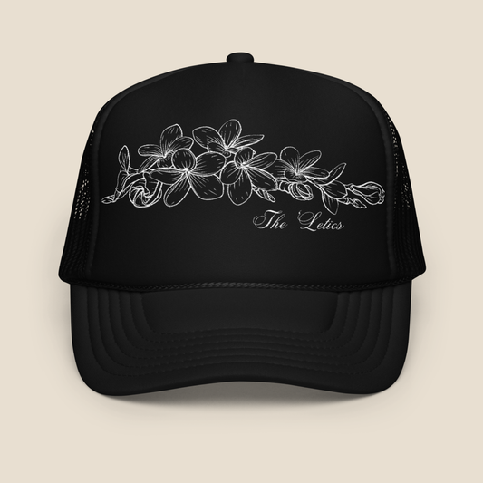 Black foam trucker hat with embroidered Champei or also known as Plumeria flower, front view.